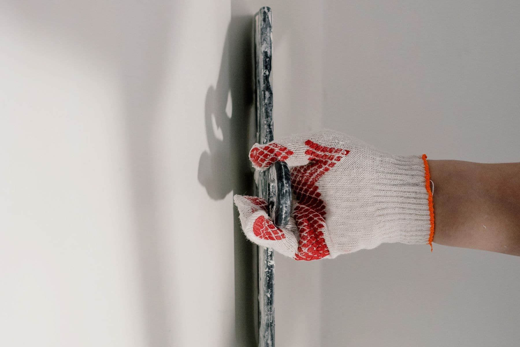 Handwerker glättet eine Innenwand mit einer breiten Spachtelkelle