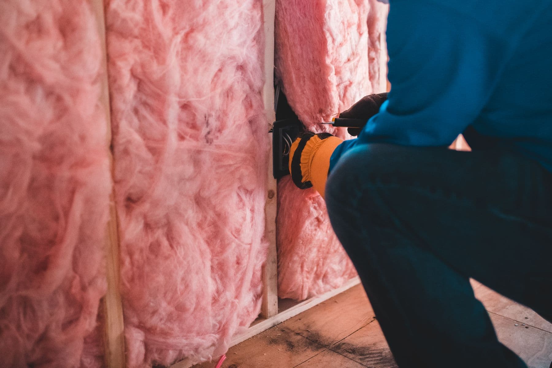 Handwerker setzt Dämmstoff zwischen die Ständer einer Trockenbauwand ein