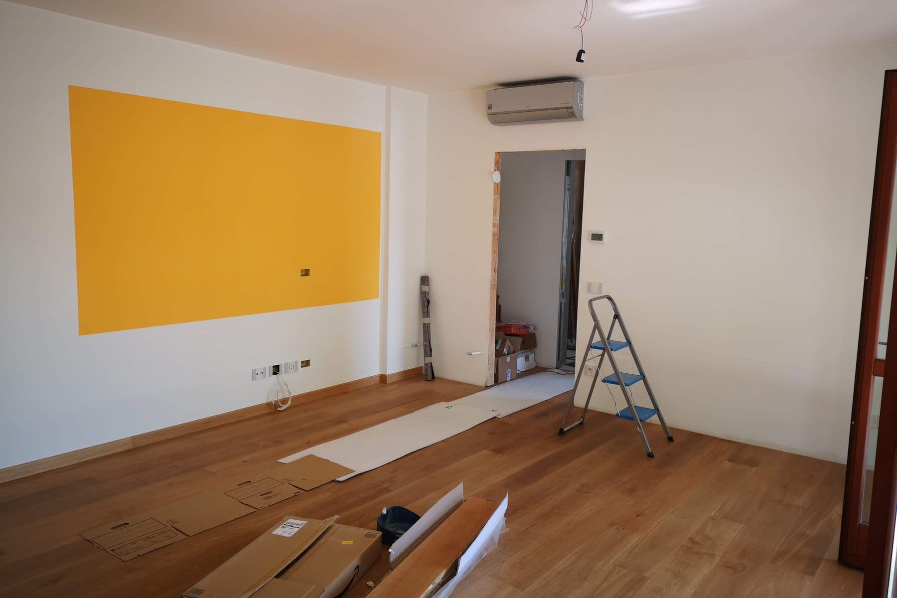 Wohnraum während der Renovierung mit Leiter, Material und teilweise fertigen Oberflächen