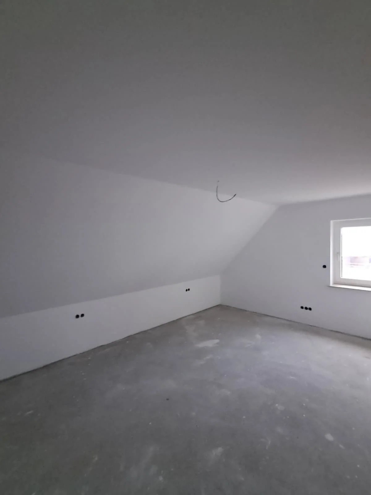 Heller Dachgeschossraum mit fertig bearbeiteten Wand- und Deckenflächen